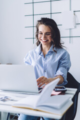 Happy woman working at laptop while sitting at desk