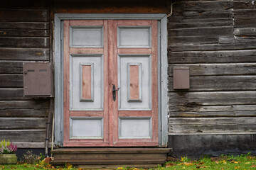 Vintage pink and grey door on the exterior of old wooden house. Painted front entrance of a wooden house. Wooden door background. 