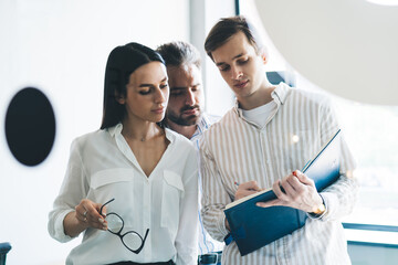 Man writing in notebook while standing in office