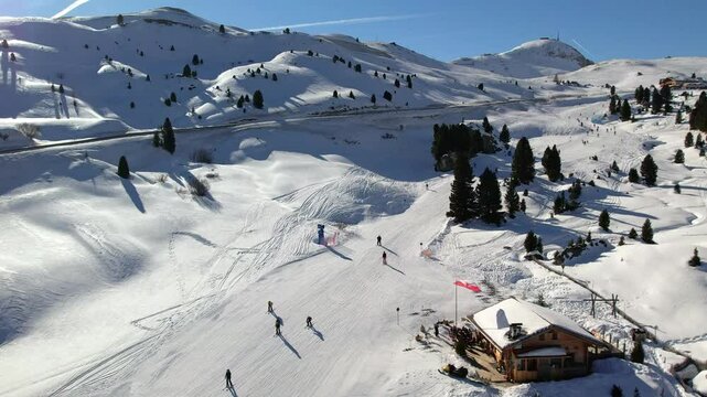 A serene view of a ski resort in the Dolomites, featuring skiers enjoying the snowy slopes and a cozy cabin in Dolomiti Superski