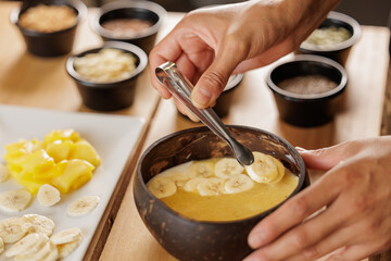 Cook's hands preparing a bowl of fruit smoothie in the cafeteria kitchen. Woman preparing healthy breakfasts and snacks for children, mothers, pregnant women, athletes.