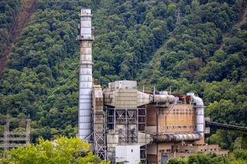Power Plant Smokestack Amid Lush Green Forest Landscape..