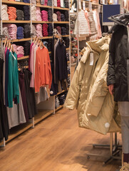 A colorful collection of women's autumn and winter clothing hangs on a hanger in the store