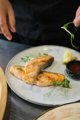 Chef Garnishing Grilled Fish with Herbs