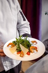 Chef Holding Plate of Shrimp and Cheese Salad