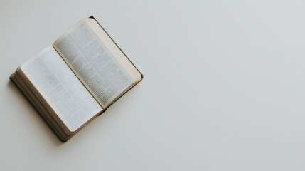 A top-view, isolated image of a book lying open on a clean, white surface. The book is positioned at an angle from the top left corner, showing both pages clearly. The cover is slightly visible, with 