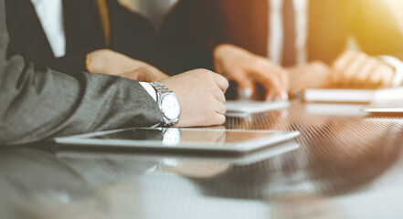 Unknown businessmen and woman sitting, using laptop computer and discussing questions at meeting in sunny office, close-up. Success concept