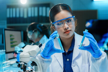 Scientist wearing a lab coat and gloves is carefully examining test tubes in a laboratory setting
