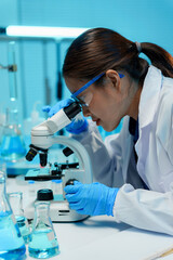 Scientist wearing gloves and safety glasses is using a microscope and doing research in a laboratory