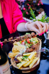 Grilled skewers with crinkle fries, pita, and salad, delicious outdoor dining experience