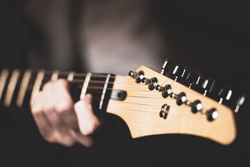 A guy playing an electric guitar, close-up of his hand and fingerboard.