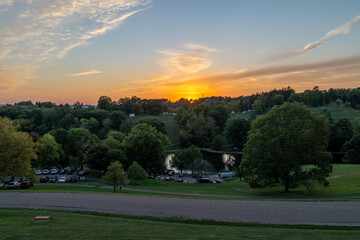 Serene Sunset Over Park with Trees and Reflection.