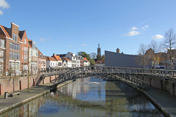 Obraz premium a beautiful cityscape of a little historic town 'Hulst' in Holland, with canal houses at the quay of the canal with a bridge and the basilica in the background