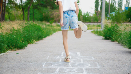 Close-up of a girl feet and hopscotch painted on the asphalt. A child plays hopscotch on an outdoor on a sunny day. outdoor activities for children.