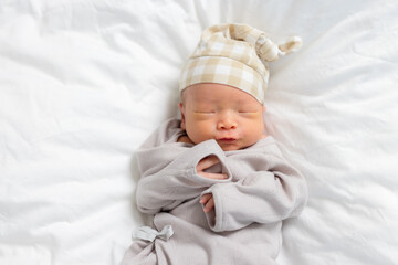 Asian newborn baby with hat sleep on bed