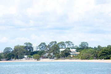 Tranquil Coastal Shoreline: A serene vista of a coastal town nestled amidst lush greenery and a tranquil blue ocean, evoking a sense of peace and tranquility. Sunny tropical beach with palm trees and 