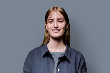Obraz premium Portrait of beautiful young woman with blond hair looking at camera on grey background