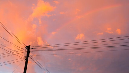 A light purple-orange sun, an electric pole with cluttered electrical lines.