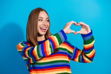 Photo of charming cheerful girl wear striped colorful clothes arm heart sign isolated on blue background