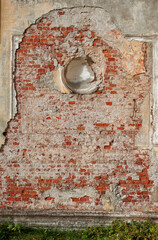 Cracked plaster exposes red brick underneath, creating a rustic texture