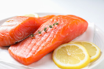 Pieces of fresh salmon with thyme and lemon on white table, closeup
