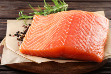 Piece of fresh salmon and spices on wooden table, closeup