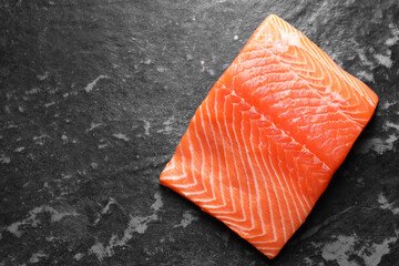 Piece of fresh salmon on dark table, top view. Space for text