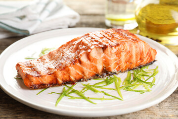 Delicious grilled salmon fillet served on wooden table, closeup