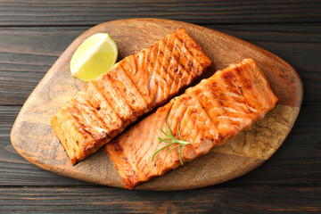 Delicious grilled salmon fillets with lime and rosemary on wooden table, top view