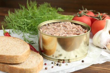 Canned meat in tin can served on wooden table, closeup