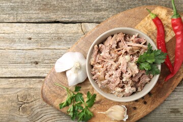 Canned meat in bowl and fresh products on wooden table, top view. Space for text