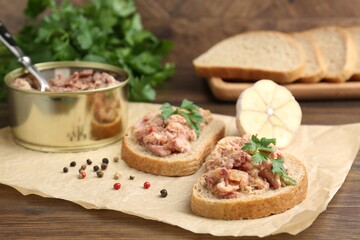 Sandwiches with canned meat, parsley, garlic and peppercorns on wooden table, closeup