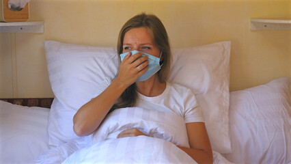 Woman wearing medical mask lying in bed, illustrating health precautions during pandemic. Self-Isolation and Health Safety