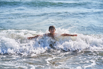 An 11 year old boy in having fun in the sea waves.