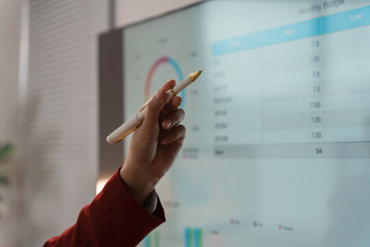Businesswoman is pointing at a digital interactive whiteboard showing financial data during a presentation - Powered by Adobe