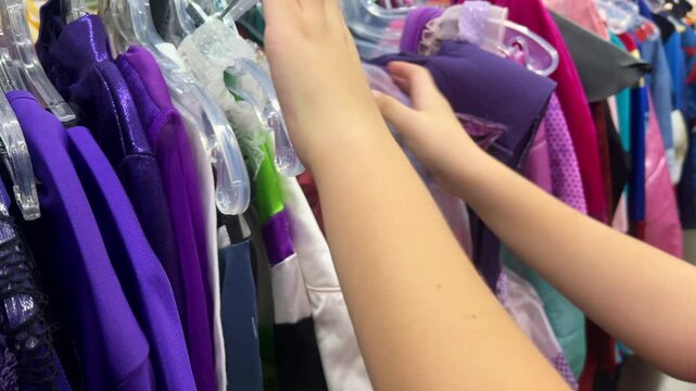 Close up of a person looking through used Halloween costumes at a thrift store