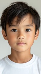 明るい目をした白いシャツを着た、ニュートラルな背景の幼い子供のポートレート