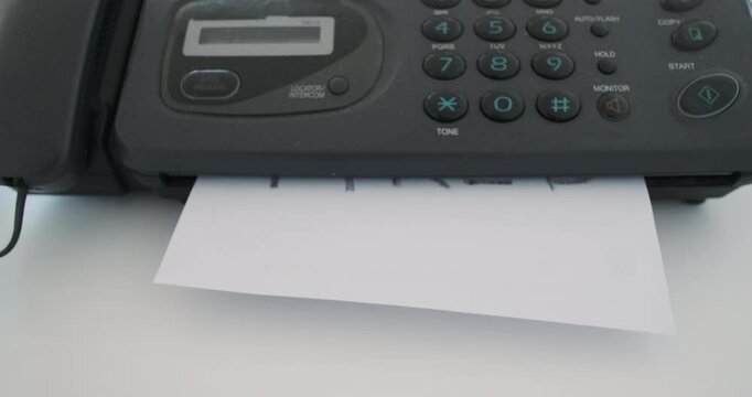 An employee receives a notice fired by fax. Retro office device, a sheet of paper with a notice of layoffs.