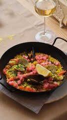 Seafood Paella with Shells and Lemon in Pan with Wine Glass