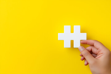 Obraz premium Hand holding white hashtag symbol on bright yellow background, minimalist social media concept