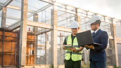 Fototapeta premium Two construction engineers inspect the building structure and the progress of the construction plan
