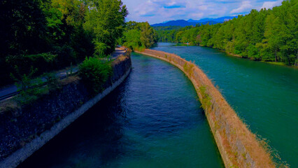 Fototapeta premium Trezzo sul Adda, Italy. Aerial view of a mountain freshwater river with low water level surrounded by green trees. White swans on the river. Forest. Hydroelectric power station. Green planet. Ecology