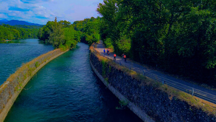 Trezzo sul Adda, Italy. Aerial view of a mountain freshwater river with low water level surrounded by green trees. White swans on the river. Forest. Hydroelectric power station. Green planet. Ecology