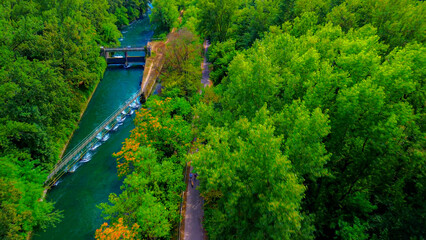 Trezzo sul Adda, Italy. Aerial view of a mountain freshwater river with low water level surrounded by green trees. White swans on the river. Forest. Hydroelectric power station. Green planet. Ecology