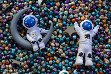 Cute astronaut figurines on colorful decorative beads with moon and stars, whimsical outer space concept for children. © Ksenia
