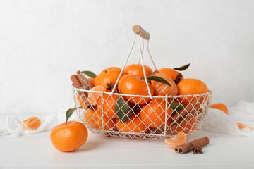 Basket of sweet mandarins with cinnamon and star anise on white wooden table