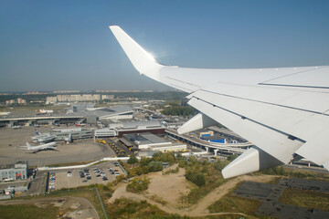 The plane is taking off. View from the window to the wing of the aircraft, runway, airfield and sky.