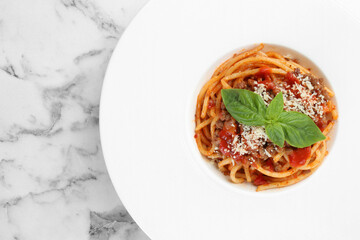 Delicious pasta bolognese with basil on white marble table, top view