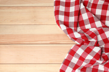 Obraz premium Crumpled tablecloth with checkered pattern on light wooden table, top view. Space for text