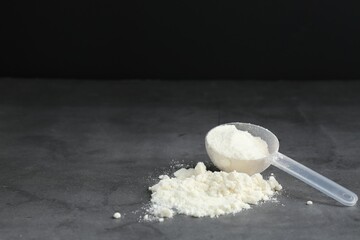 Protein powder and scoop on grey textured table, space for text